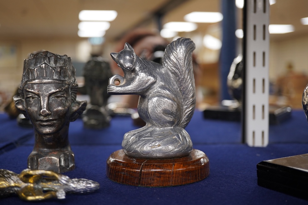 Seven chrome, brass and aluminium car mascots, etc. including an unusual and comical aluminium car mascot in the form of a squirrel holding a nut, together with a standing bear, an Art Deco winged head, a ram, a running
